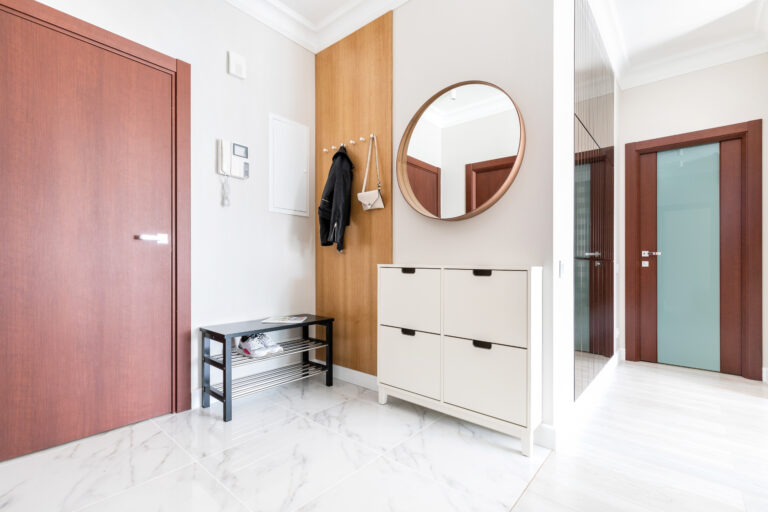 modern house hallway with white shoe closet and rounded mirrow